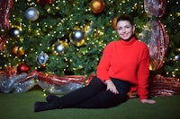 a woman sitting in front of a christmas tree